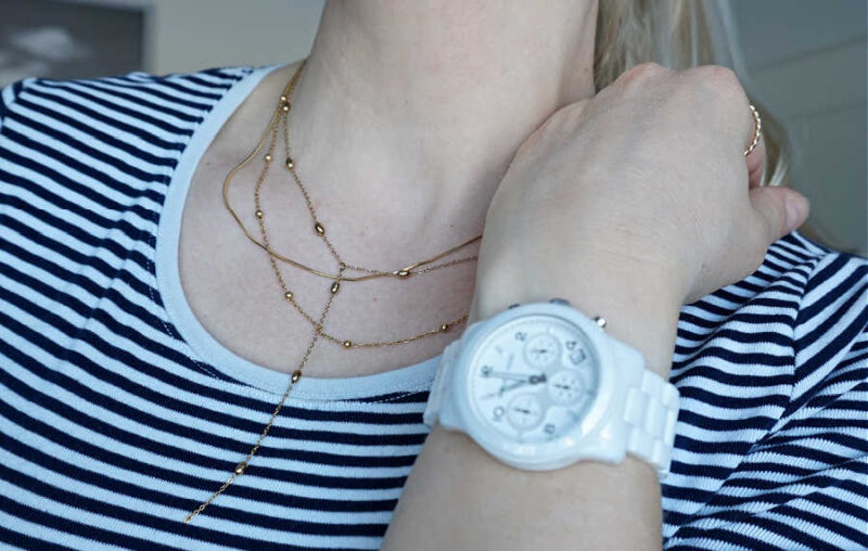 layered gold necklace and white ceramic watch